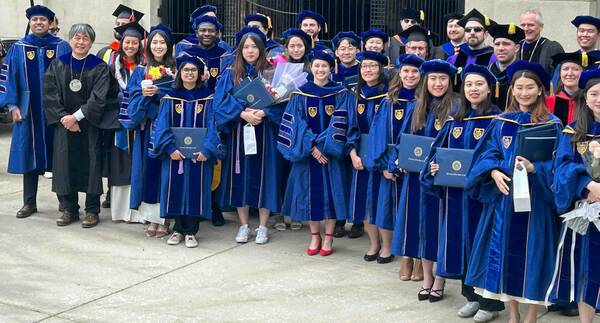 2025 CBE Graduating Class. all standing in front of stadium in PhD and Masters Commencement Robes.